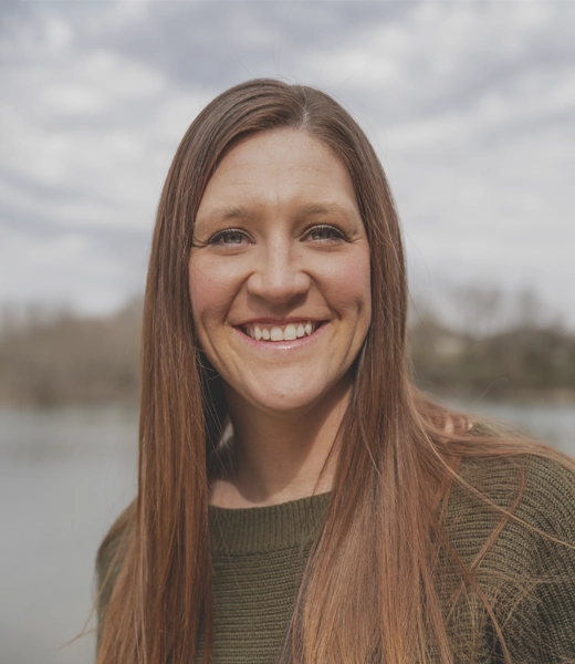Chiropractor Chester OH Sarah Cook Welcome R HP Dr. Sarah Cook with her hair down, wearing a green blouse and a big smile, with a beautiful sky in the background.